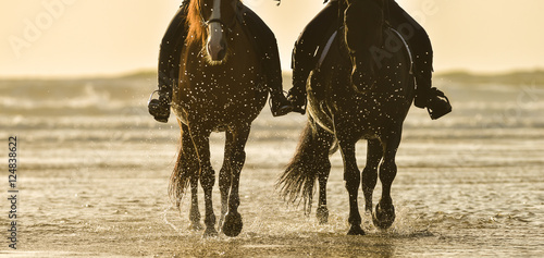 Horse riding on the beach at sunset