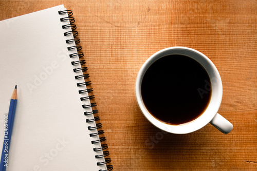 Top view of notebook, pencil and coffee on wood background