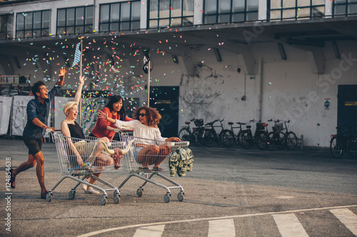 Multiethnic young people racing with shopping trolleys photo