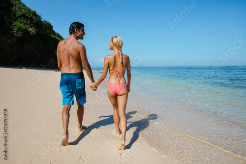 Honeymoon couple holding hands walking on beach