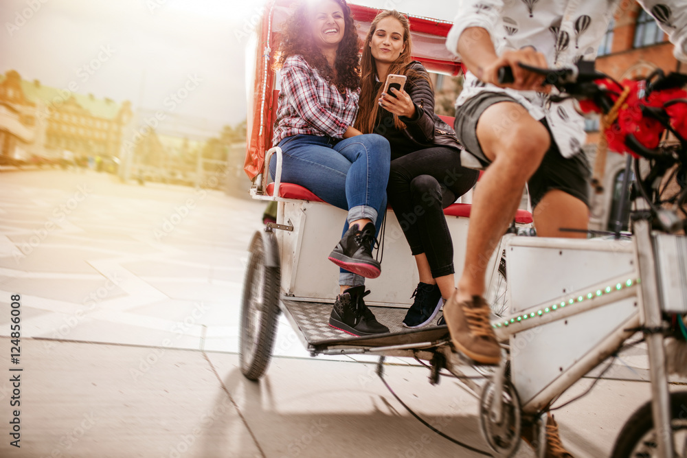 Obraz premium Young women sitting on tricycle and posing for selfie