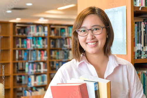 In the library - Aisian female student with books working in a u photo