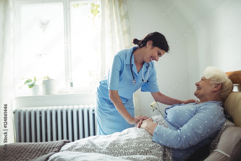 Fototapeta premium Nurse interacting with senior woman on bed
