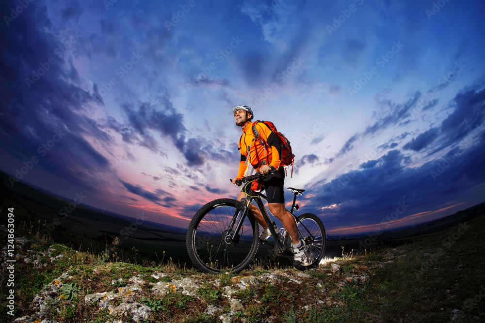 Obraz premium Man in helmet stay on bicycle under sky with clouds.