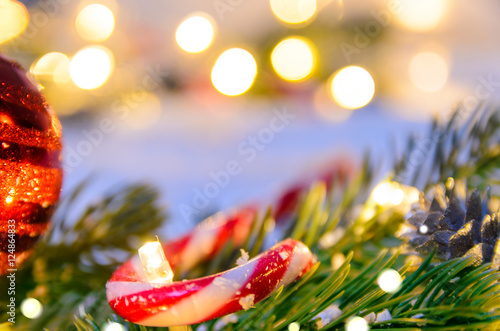 Christmas fir tree with lights and candy cane on snow in dark  view from above