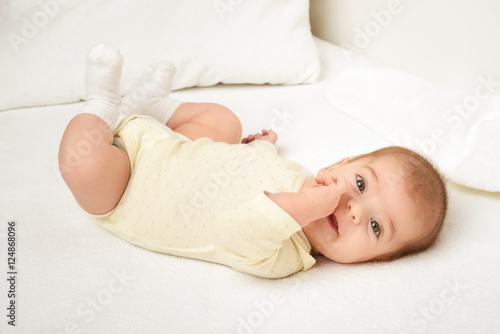baby portrait lie on white towel in bed, yellow toned