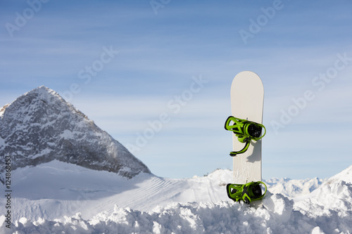 Snowboard in snow slope on a beautiful mountain background