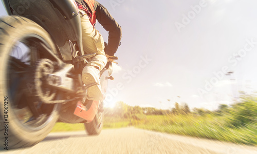 Man is riding a motorcycle on the asphalt road photo