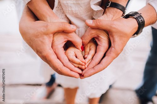 Obraz na płótnie A family of hands form a heart - father on the outside, then mother's hands and infant baby hands in the middle. w salonie