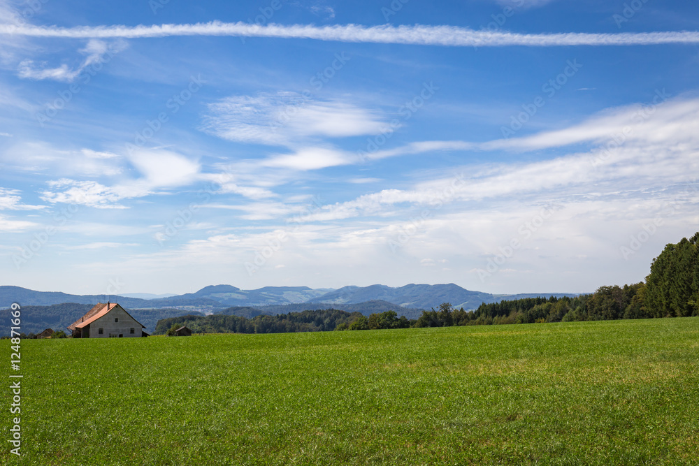 Contrail across blue sky with mountains far away Contrail across blue sky with mountains far away