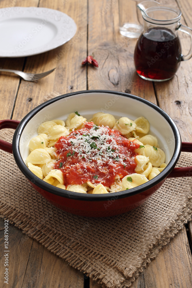 pasta italiana orecchiette pomodoro e formaggio in tegame di metallo sfondo legno rustico pasta italiana orecchiette pomodoro e formaggio in tegame di metallo sfondo legno rustico
