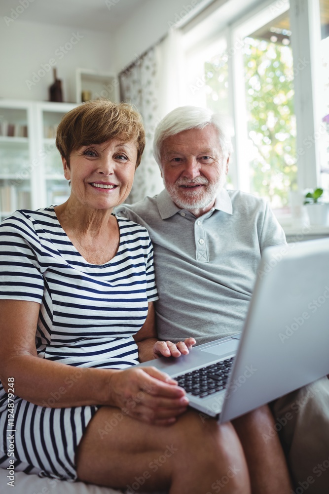 Senior couple sitting on sofa with a laptop