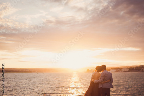 young couple watching sunrise and hugging