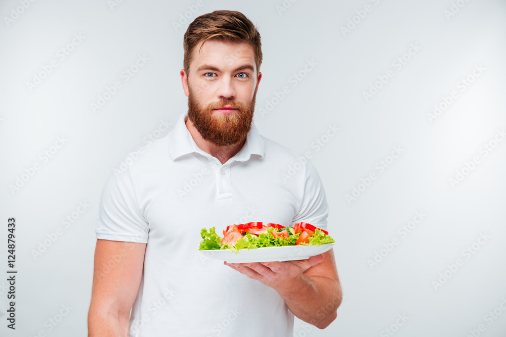 Portrait of a bearded man holing plate with fresh salad Portrait of a bearded man holing plate with fresh salad