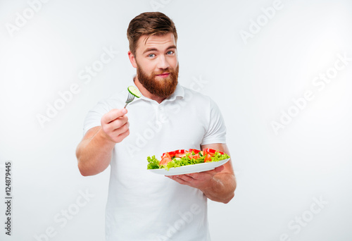 Young bearded man eating salad