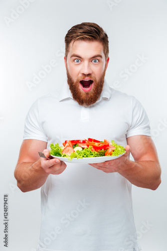 Young man holding fork to eat fresh vegetable salad meal