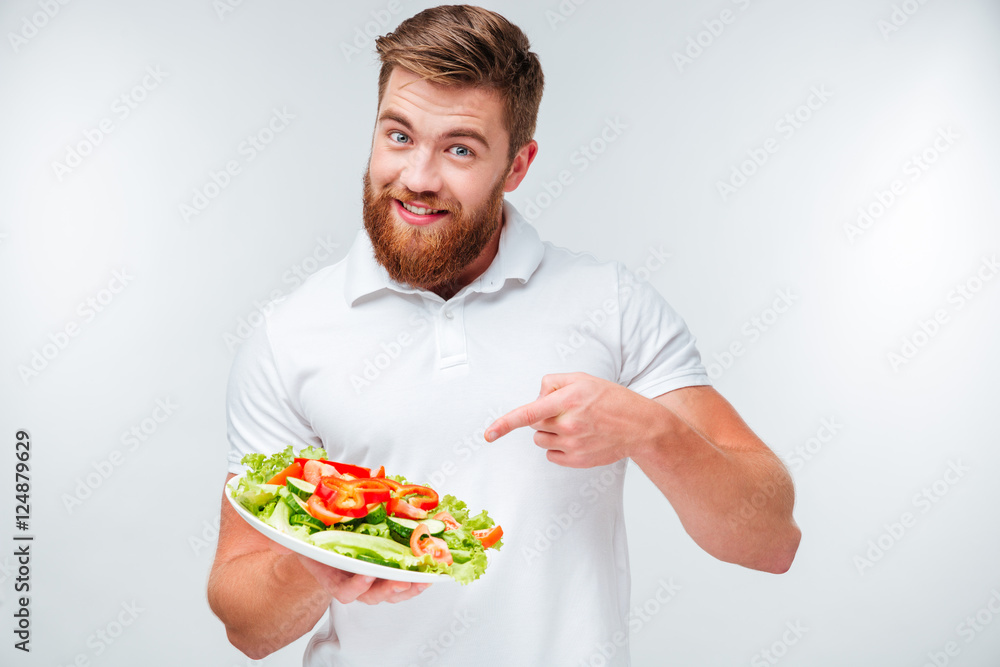 Happy bearded man pointing finger at plate with fresh salad Happy bearded man pointing finger at plate with fresh salad