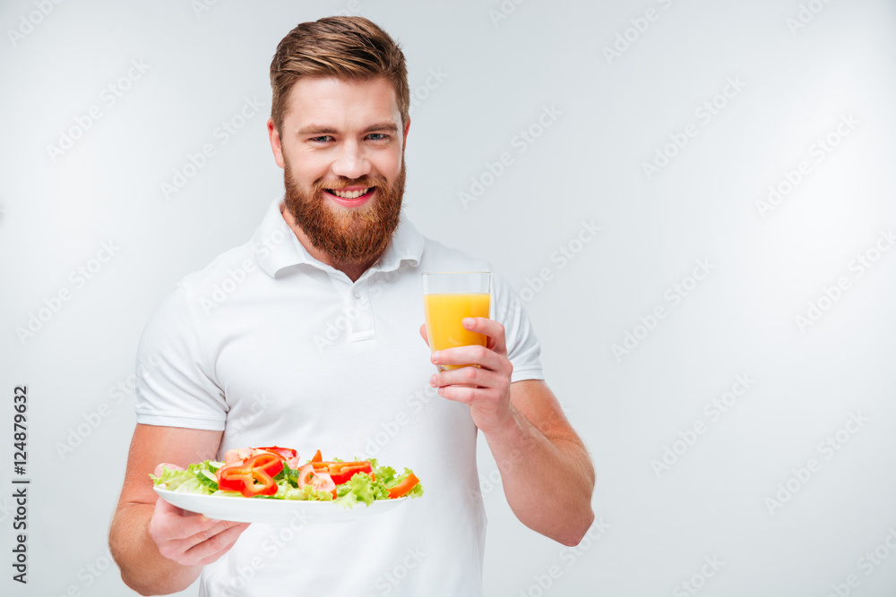 Man holding plate with vegetables and glass of orange juice Man holding plate with vegetables and glass of orange juice