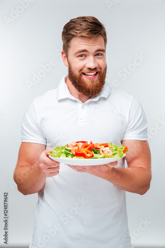 Happy cheerful bearded man holding plate with vegetables
