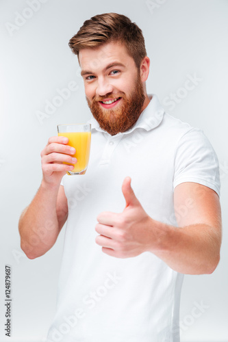 Man holding glass of orange juice and showing thumbs up