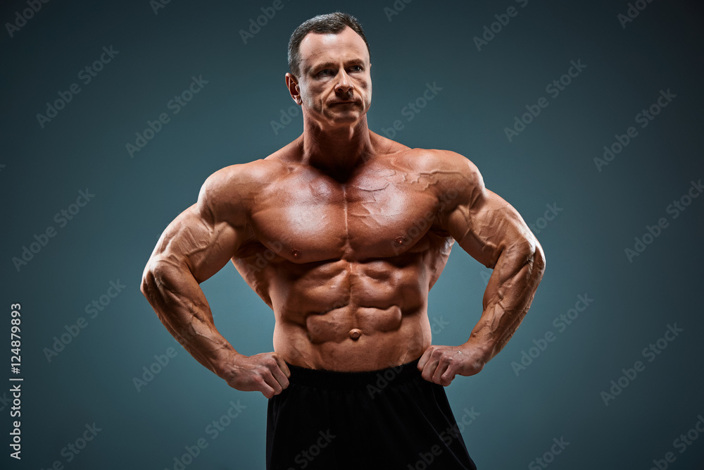torso of attractive male body builder on gray background. torso of attractive male body builder on gray background.