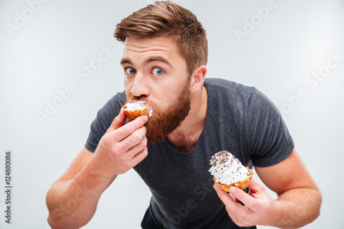 Close up portrait of a hungry man biting cream cake