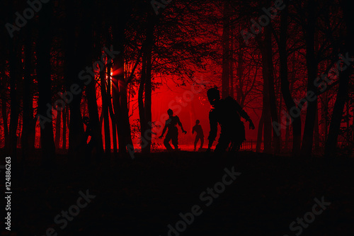 bloodthirsty zombies attacking. hungry zombies in the woods. Silhouettes of scary zombies walking in the forest at night photo