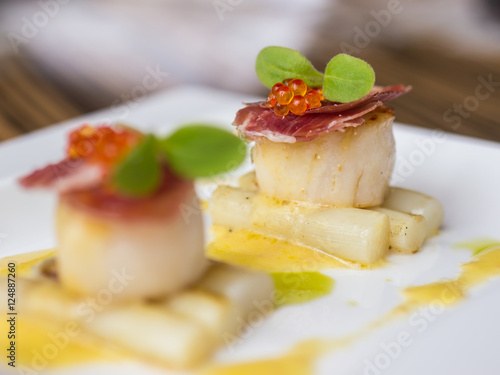 Seared scallops with salmon roe, ham and asparagus on plate