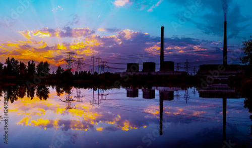 Coal power plant at sunset and reflection in water.