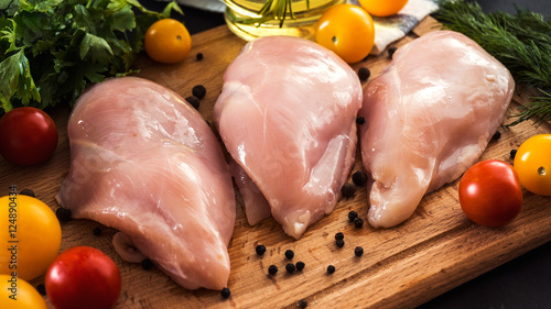 Raw chicken breast fillets and vegetable on wooden background