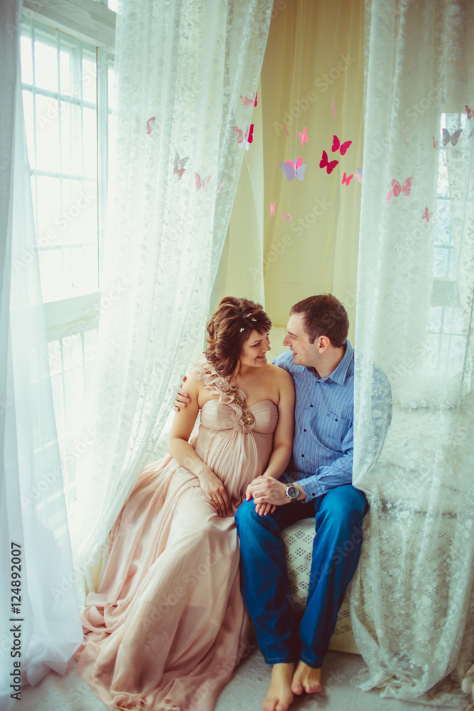 Hugging family waiting for a child sits between white curtains o Hugging family waiting for a child sits between white curtains o