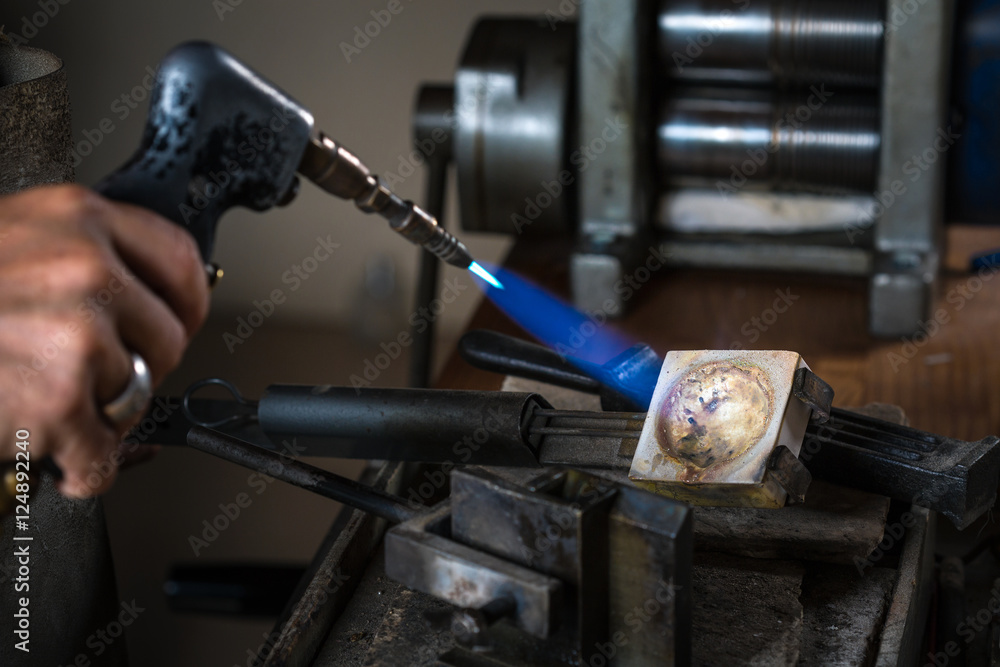Close-up of Goldsmith using a Blowtorch on Crucible in order to melting Silver Grains; Goldsmith Workshop; Close-up of Goldsmith using a Blowtorch on Crucible in order to melting Silver Grains; Goldsmith Workshop;