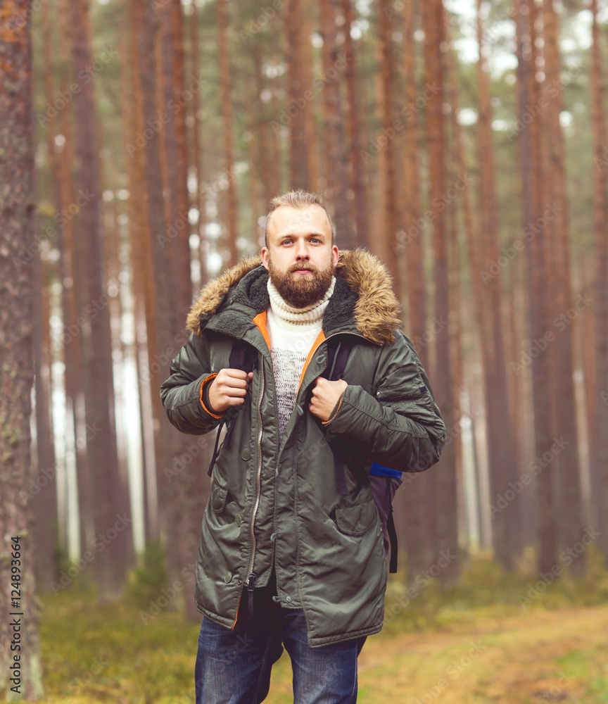 Man with a backpack and beard hiking in the forest