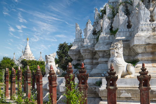 White Pagoda at Inwa ancient city with lions guardian statues. Amazing architecture of old Buddhist Temples. Myanmar (Burma) travel landscapes and destinations photo