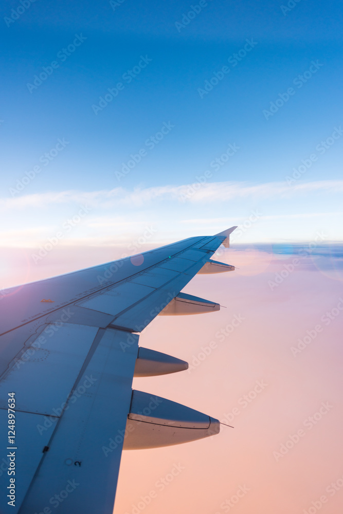 Fototapeta premium Wing of the airplane on blue and pink sky background at sunset