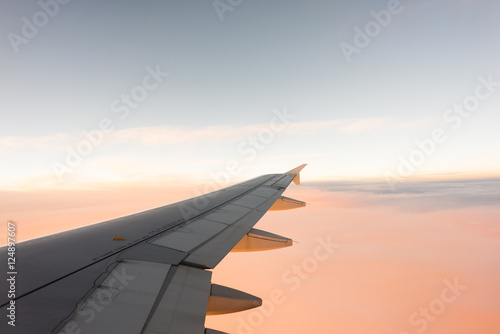 Wing of the airplane on pink sky background at sunset