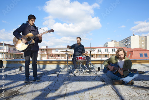 Full length shot of a pop band playing music on outdoor scene. 