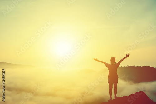 Silhouette of woman praying over sea of mist over mountain for background