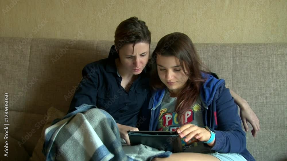 Two lesbian girlfriends using tablet on the coach Two lesbian girlfriends using tablet on the coach