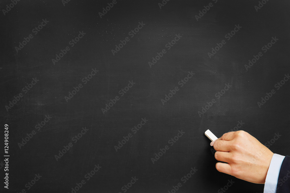 Hand with chalk on blackboard Hand with chalk on blackboard