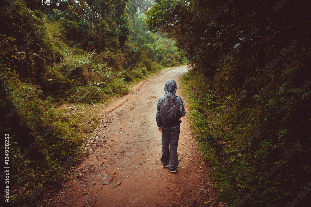 Boy with backpack walks on a road