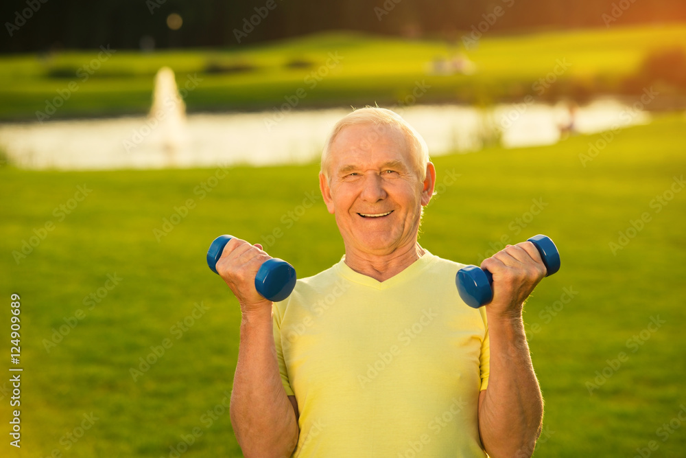 Senior man with dumbbells smiling. Old guy on nature background. Lift weights to become stronger. Sport is my life. Senior man with dumbbells smiling. Old guy on nature background. Lift weights to become stronger. Sport is my life.