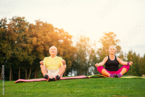 Senior couple doing yoga. People sitting outdoors. Body and mind. In harmony with nature.