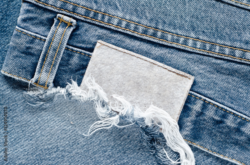 Fotka „Jeans background texture,Blank real leather jeans label sewed on old  worn jeans.Denim jeans texture or denim jeans background with label.Denim  jeans texture or denim jeans background with old torn.“ ze služby