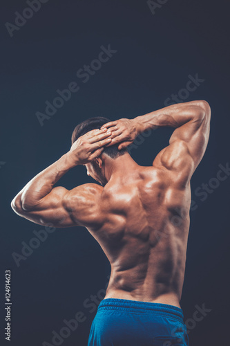 Strong athletic man back on dark background