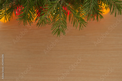 Christmas Greeting Card. Fir Branch with red and gold lights on a wooden background. Happy New Year.