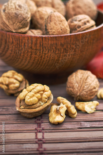 Walnuts in wooden bowl on wooden background