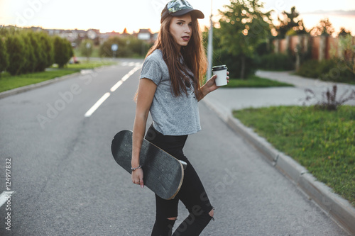 skater girl with coffee cup in front of the sun starts her day.
