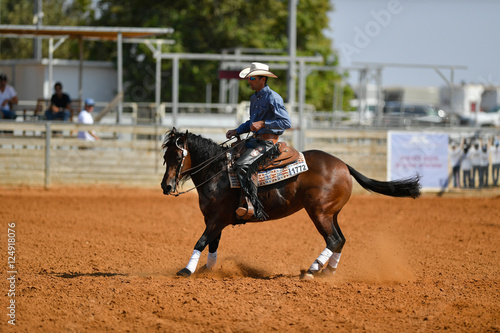 The side view of a rider in cowboy chaps, boots and hat on a horseback performs an exercise during a competition © PROMA