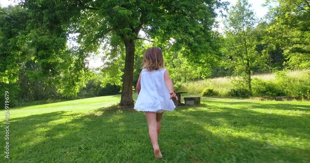 happy little girl running in a beautiful garden with her baby to the sunbeams in nature . concept of happiness nature and happy childhood happy little girl running in a beautiful garden with her baby to the sunbeams in nature . concept of happiness nature and happy childhood